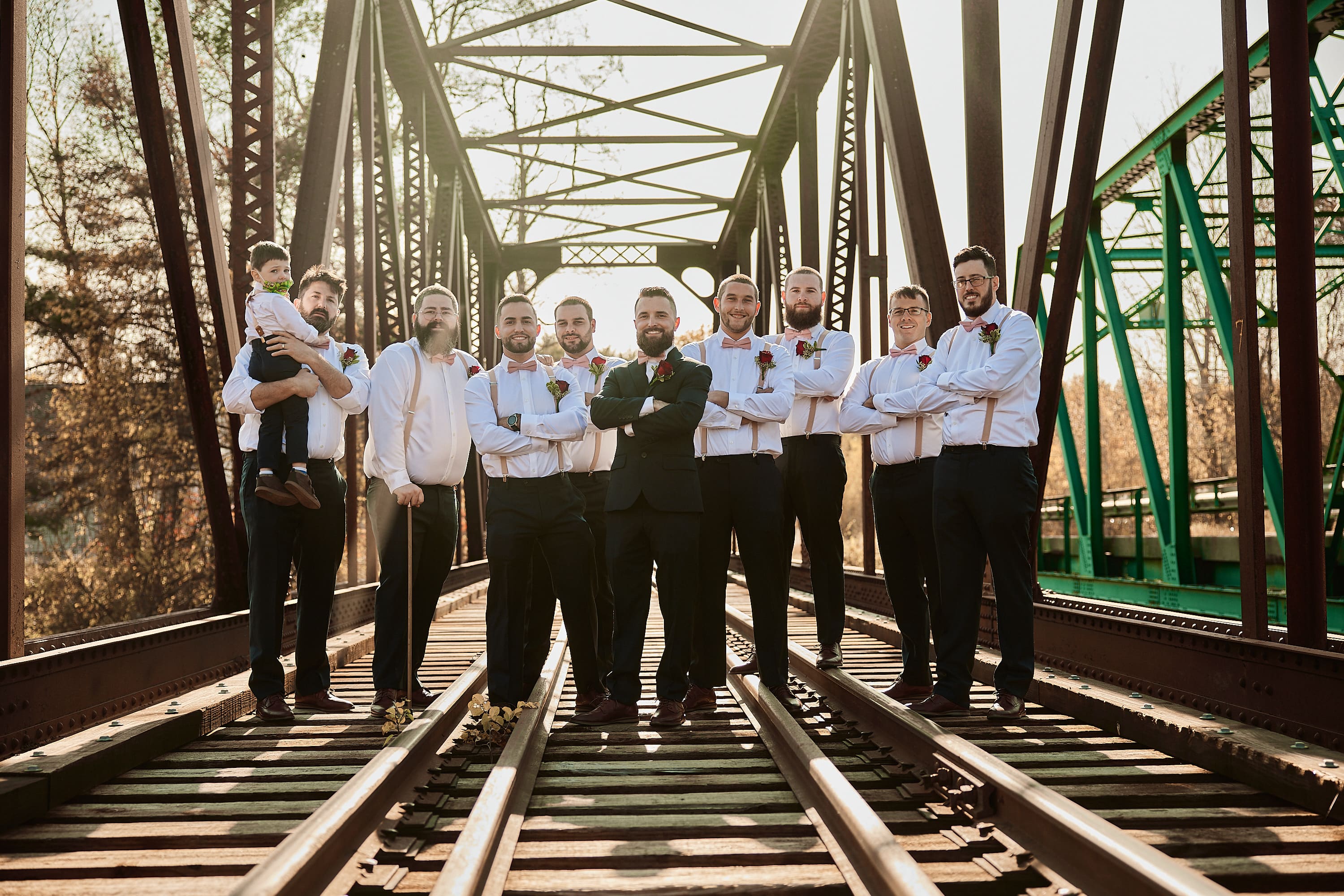 Group photo of groomsmen walking across a bridge in Boston